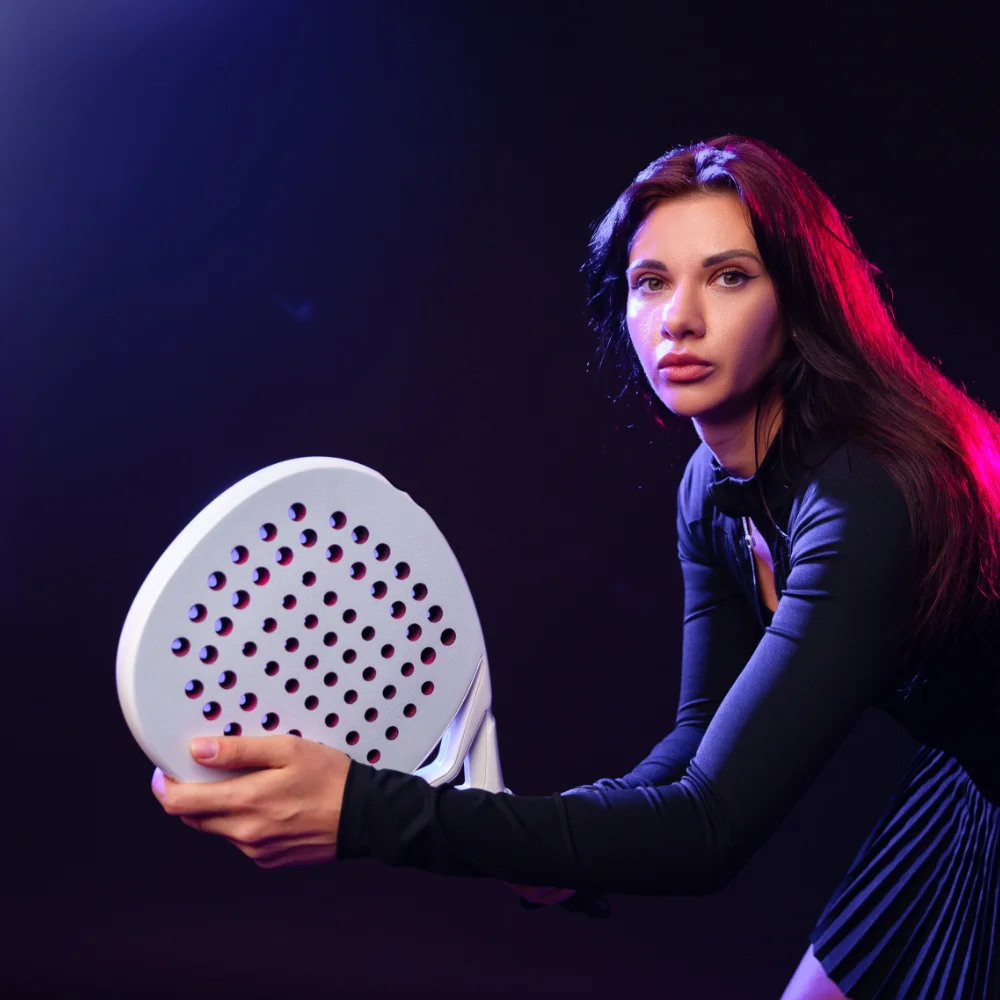 Female padel player holding a racket and preparing for play in a studio setting