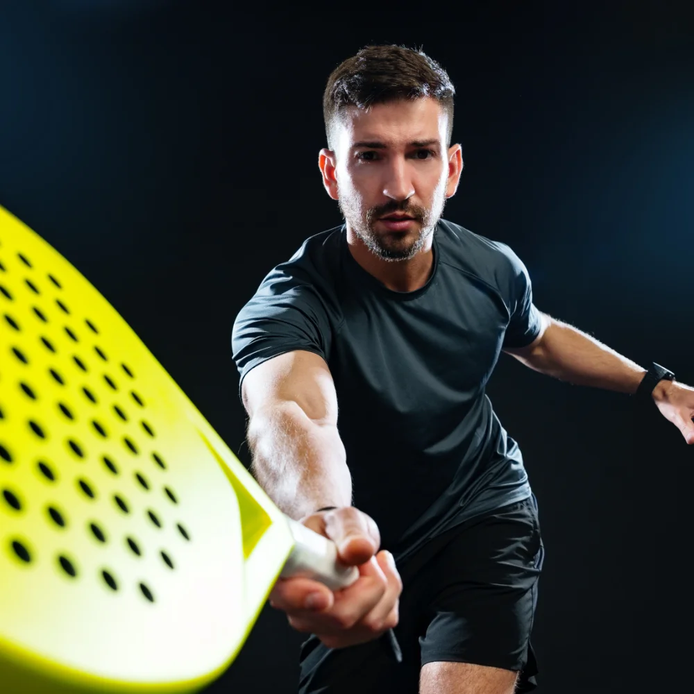 Male padel player reaching forward to hit the ball with a padel racket